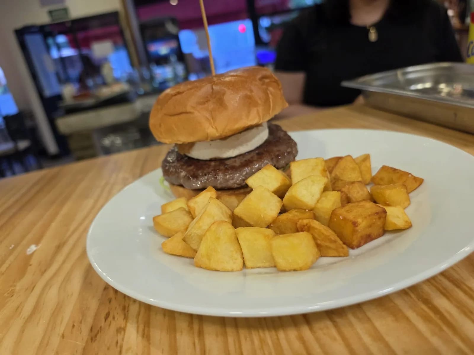 Hamburguesa con queso de cabra y cebolla caramelizada acompañada de patatas en dados